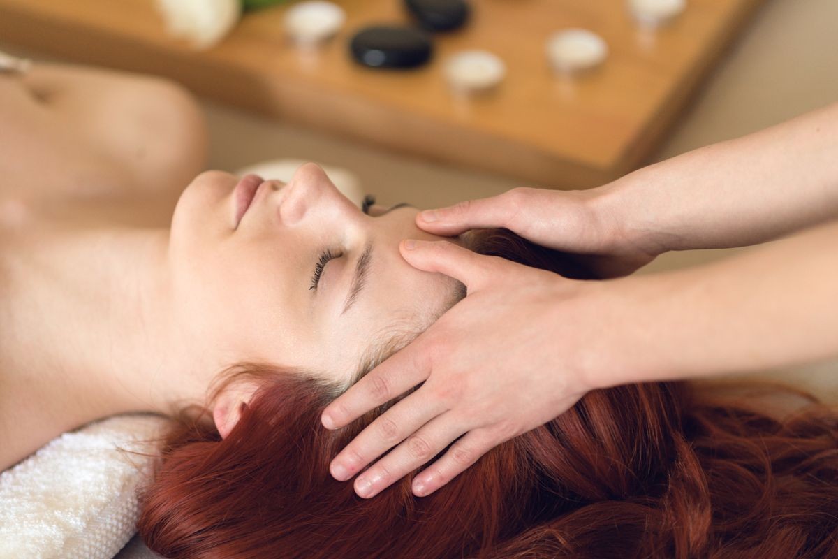 Young woman having her head massage at a spa center 