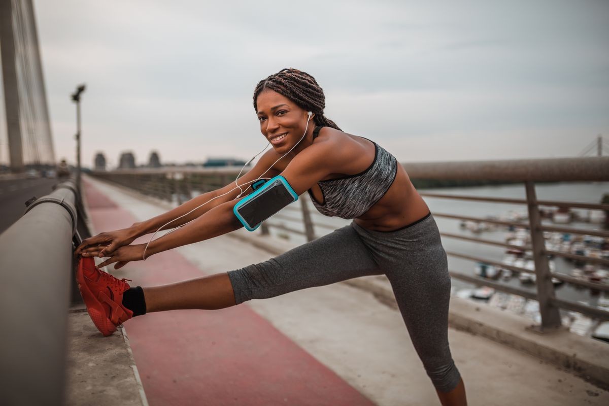Young black woman in sportswear is doing stretching exercises outdoors